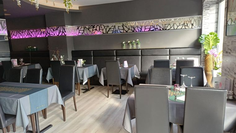 Ein modernes Restaurant mit eleganten Tischen und Stühlen. Die Wände sind stilvoll dekoriert und die Beleuchtung schafft eine angenehme Atmosphäre.