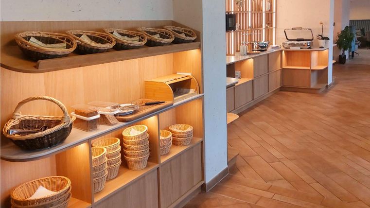 Ein schöner, heller Raum mit Holzregalen. Auf den Regalen sind verschiedene Körbe und ein Buffet mit Essensangeboten zu sehen.