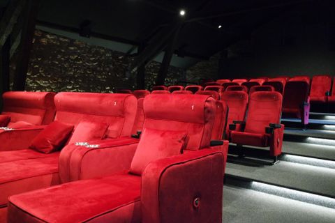Een moderne bioscoop met rode, comfortabele stoelen en een stijlvolle sfeer. De verlichting zorgt voor een aangename stemming.