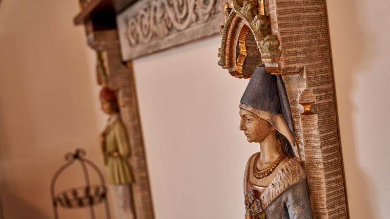 An artistic veranda with decorative statues and an elegant frame. The figures are dressed in traditional clothing and give the space a nostalgic charm.