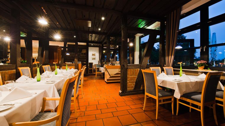 Een stijlvol restaurant met elegante tafels en gezellige verlichting. De grote ramen bieden een uitzicht naar buiten.