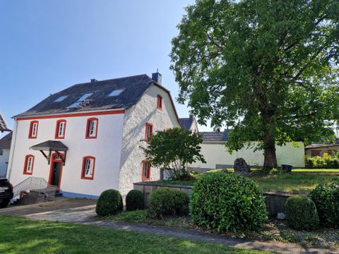 The photo shows the exterior view of the holiday home "Das Gloria". It is the old rectory in Uedelhoven, municipality of Blankenheim in the Eifel, built in 1807 and extensively renovated in the period 2024/2025 by the owner Kirsten Mauer in coordination with the heritage conservation authority.
