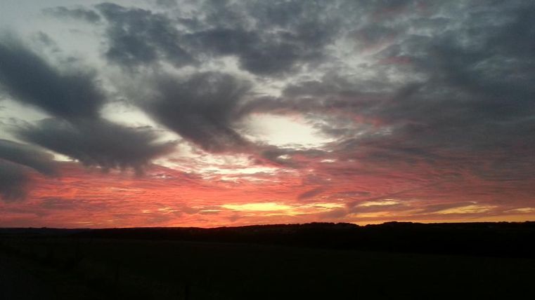 A beautiful sunset with brightly colored red and orange clouds. The sky is surrounded by a dramatic cloudscape.