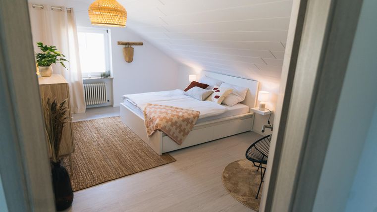 Een heldere slaapkamer met een groot bed en gezellige decoratie. De ruimte heeft een vriendelijke sfeer en een mooi tapijt.