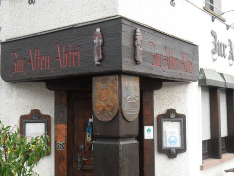 A traditional inn named "Zur Alten Adlerei". The entrance area features intricate wood carvings and old coats of arms.