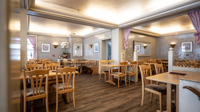 A cozy restaurant with wooden tables and chairs. The walls are tastefully decorated, and the lighting creates an inviting atmosphere.