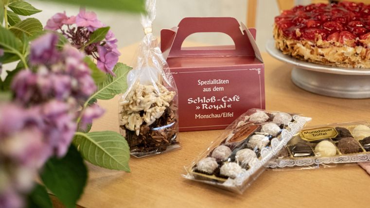 A table with various sweets and a cake. In the foreground, chocolates and a paper bag with snacks are visible.