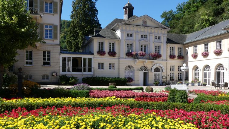 Een schilderachtig gebouw omgeven door kleurrijke bloembedden. De sfeer is uitnodigend en rustig.