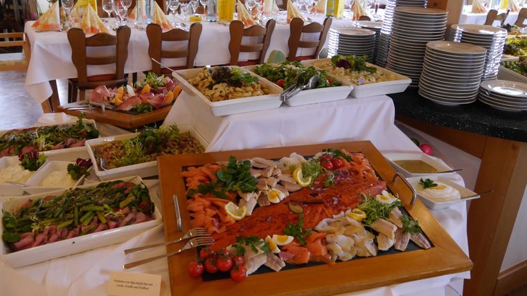 Ein reichhaltiges Buffet mit verschiedenen Salaten und Fischgerichten. Der Tisch ist schön dekoriert und bietet eine Vielzahl an frischen Speisen.