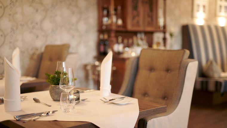 Ein elegantes Restaurant mit schön gedeckten Tischen. Gemütliche Stühle und stilvolle Dekoration schaffen eine einladende Atmosphäre.