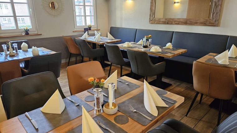 Een gezellig restaurant met elegante tafels en stoelen. De tafels zijn liefdevol gedekt en creëren een uitnodigende sfeer.