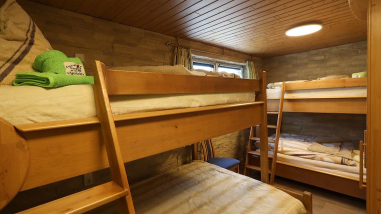 A simple room with two wooden bunk beds. The walls are light and the room has a cozy atmosphere.
