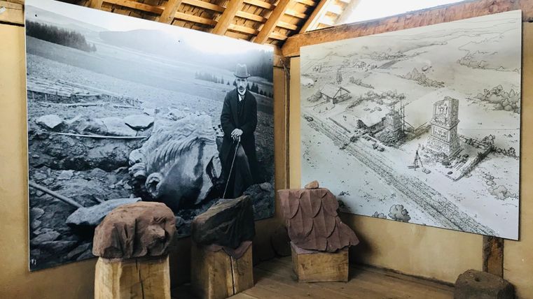 Innenansicht eines Museums mit zwei großen historischen Bildern an der Wand und drei Steinskulpturen auf Holzsockeln.