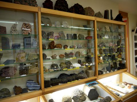 Ein Regal mit vielen verschiedenen Gesteinen und Mineralien. Die Sammlung ist gut erschlossen und zeigt eine Vielzahl an Farben und Formen.