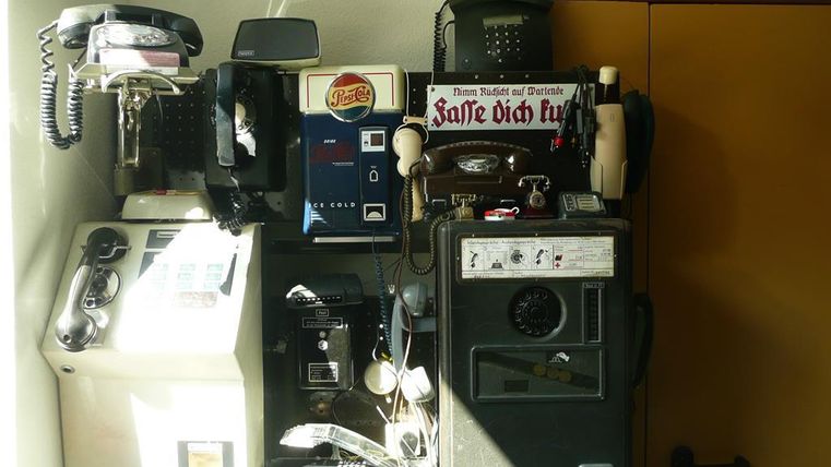 Eine Sammlung alter Telefone und Geräte, darunter Wählscheibentelefone und ein Pepsi-Cola-Automat, im Telefonmuseum Gerolstein.