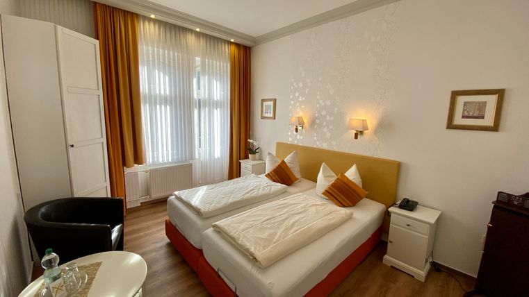 Ein gemütliches Schlafzimmer mit zwei Einzelbetten und warmen Farbtönen. Der Raum ist hell erleuchtet und bietet ein angenehmes Ambiente.