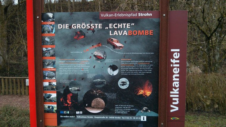 An information sign about the largest real lava bomb in the Eifel. It displays images and explanations about volcanic activity and geological formations.