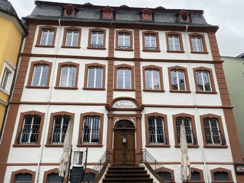 A historical building with a white and red facade. The facade features several windows and a central entrance door.