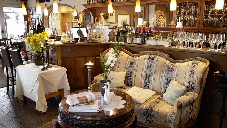 Ein einladendes Restaurant mit einem gemütlichen Sitzbereich und einer gut sortierten Bar. Der Raum ist hell und stilvoll mit Blumenarrangements dekoriert.