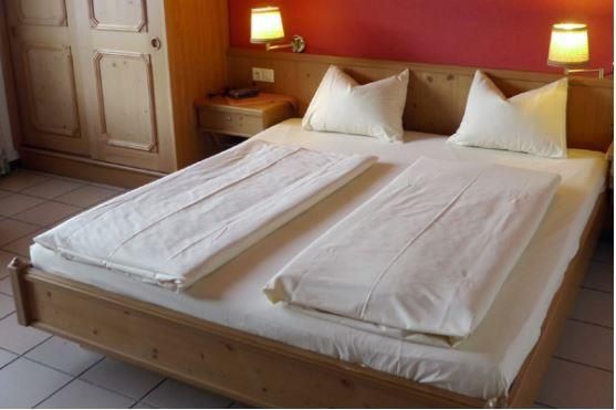 Ein gemütliches Schlafzimmer mit einem Holzbett und zwei separaten Decken. An den Wänden befinden sich Holzpaneele und es gibt sanfte Beleuchtung.