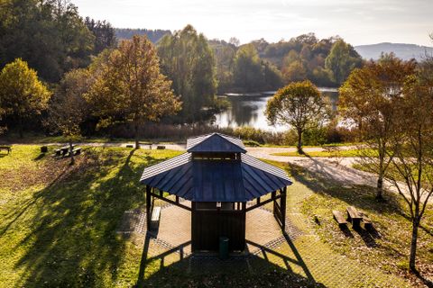 View of a lake with trees in the background, information pavilion in the foreground