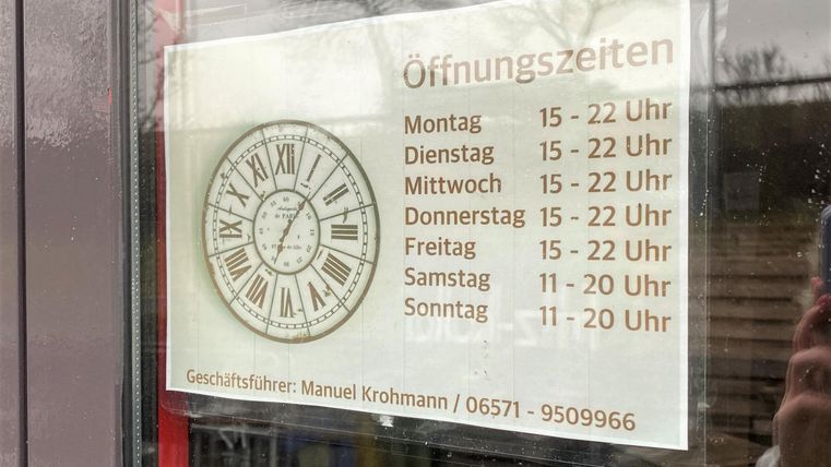 A sign with the opening hours of a business. The times are listed from Monday to Sunday.