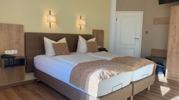 Ein gemütliches Hotelzimmer mit einem Doppelbett und modernen Möbeln. Sanftes Licht sorgt für eine einladende Atmosphäre.