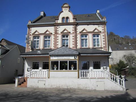 Two-story building with a classic facade, sign 'Restaurant Poseidon', Greek specialties. Staircase and railing in the foreground.