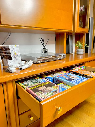 A beautiful wooden desk with an open drawer. Inside are various games and books, while on the surface some decorative items are visible.