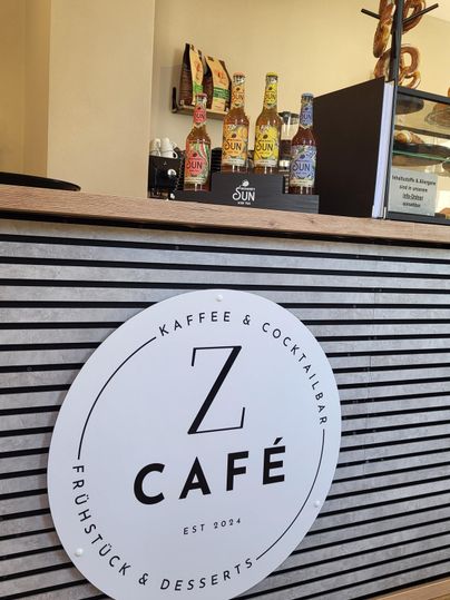 Een stijlvol café met een modern ontworpen balie. Op de balie staan verschillende drankflessen en het logo van het café is goed zichtbaar.
