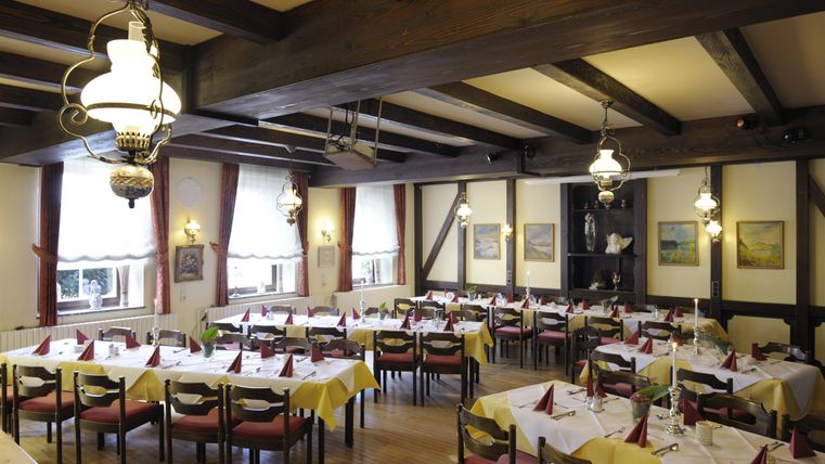 Ein gemütliches Restaurant mit Holzbalken und schön gedeckten Tischen. Die Atmosphäre ist einladend und warm.