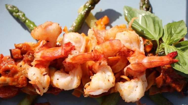 A delicious dish with shrimp, green asparagus, and fresh basil. The ingredients are arranged in vibrant colors, giving the meal an appetizing appearance.