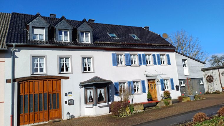 A beautiful two-story house with an inviting entrance. The sky is clear and blue, giving the surroundings a friendly atmosphere.