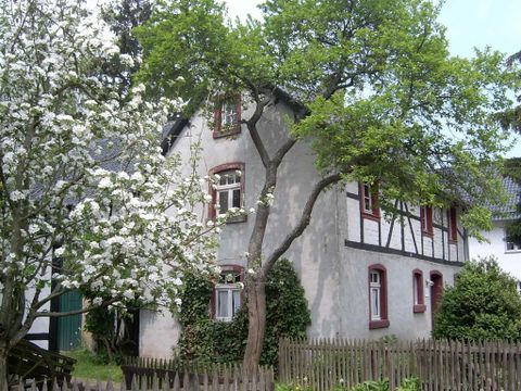 Ein charmantes Haus mit blühenden Bäumen und einem kleinen Garten. Die ruhige Atmosphäre lädt zum Verweilen ein.