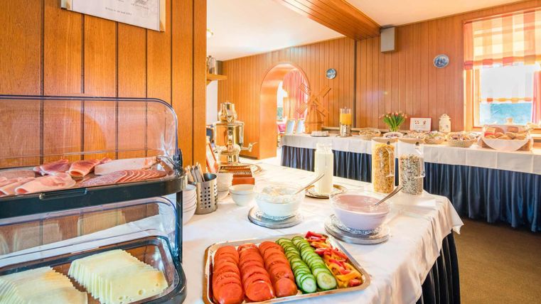 A rich breakfast buffet with cold cuts, cheese, and fresh fruit. The room is bright and welcoming, ideal for starting the day.