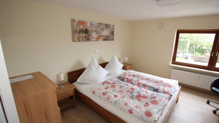 Een gezellige slaapkamer met een tweepersoonsbed en kleurrijke dekens. Er is een bureau en een groot uitzicht naar buiten.