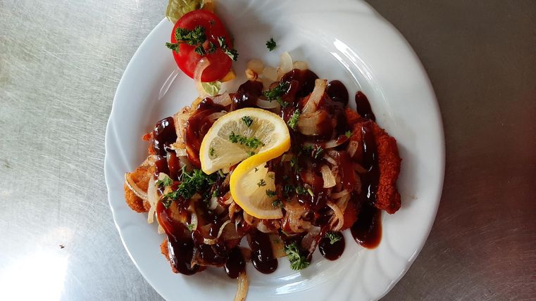 Ein Teller mit leckerem Essen, garniert mit Zitronenscheiben und Kräutern. Darüber hinaus gibt es eine Kirschtomate als Dekoration.