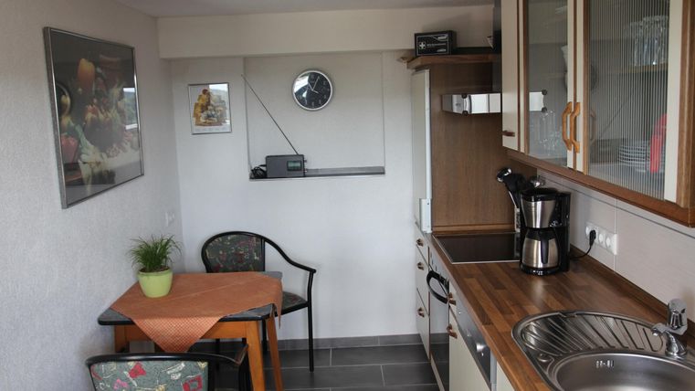 Een moderne keuken met een kleine tafel en stoelen. De ruimte is licht en goed uitgerust met kookgerei.