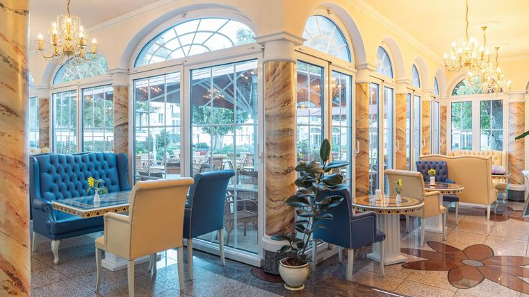 Een stijlvolle restaurant met grote ramen en elegante meubels. De heldere kleuren en de charmante inrichting creëren een aangename sfeer.