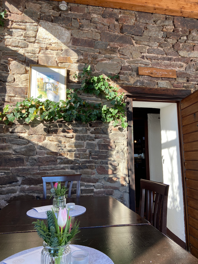 Ein gemütliches Restaurant mit einer Steinhintergrundwand. Auf dem Tisch steht eine kleine Blumendekoration.