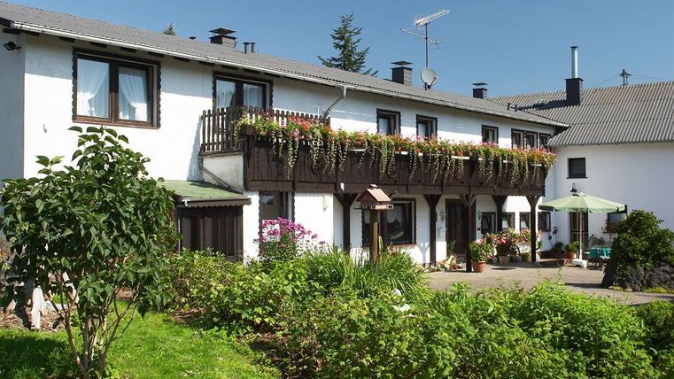 Ein charmantes Haus mit einem Balkon voller Blumen. Der Garten ist grün und einladend, ideal für entspannte Momente.