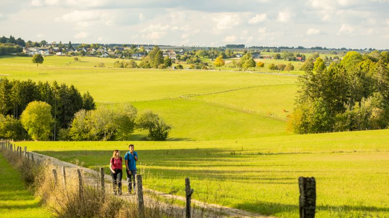 Zwei Wanderer auf einem Weg durch grüne Felder bei Hellenthal.