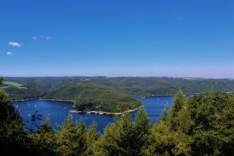 Eine malerische Landschaft mit sanften Hügeln und einem ruhigen See. Der Himmel ist klar und blau, perfekt für einen Sommertag.