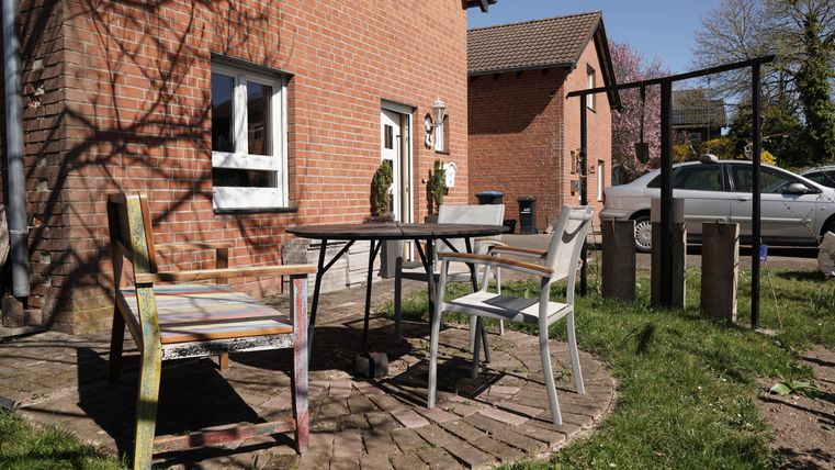Ein gemütlicher Außenbereich mit einem Tisch und zwei Stühlen. Die Umgebung ist grün und sonnig, ideal für entspannte Stunden im Freien.