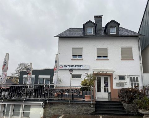 A restaurant called "Pizzeria Party" is seen in a white building. The outdoor area is equipped with umbrellas and tables.