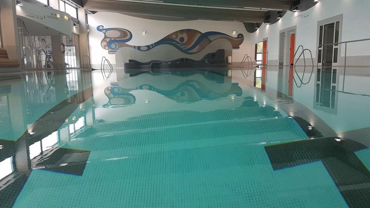 A modern-designed pool with clear water and a colorful mural. The surroundings feel inviting and calm.