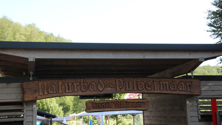 Der Eingang zum Naturbad Pulbermaarr. Eine freundliche Willkommensatmosphäre umgeben von Natur.