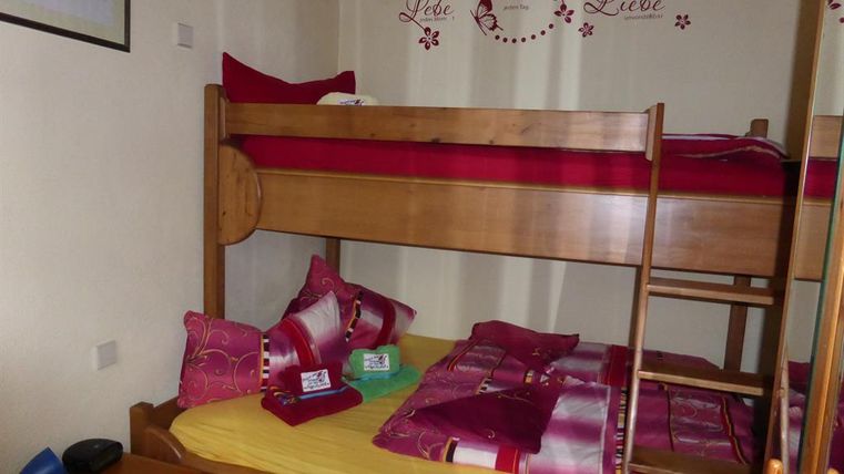 A cozy bedroom with a loft bed and a single bed. The walls are decorated with a loving quote.