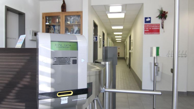 Een moderne receptie met een toegangssystem. Op de achtergrond loopt een lichte gang.