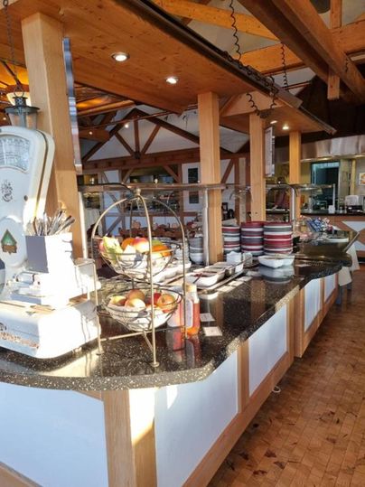 An inviting buffet with fresh fruits and dishes is set up in a cozy restaurant. The wooden interior creates a warm atmosphere.